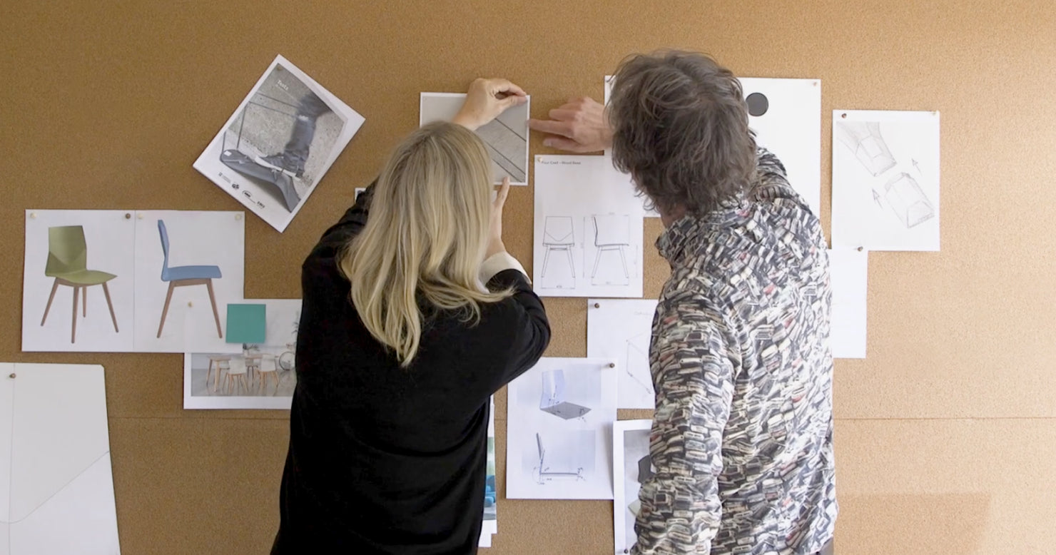 A man and woman examining a cork board displaying Four Design product prototypes and conceptual ideas.