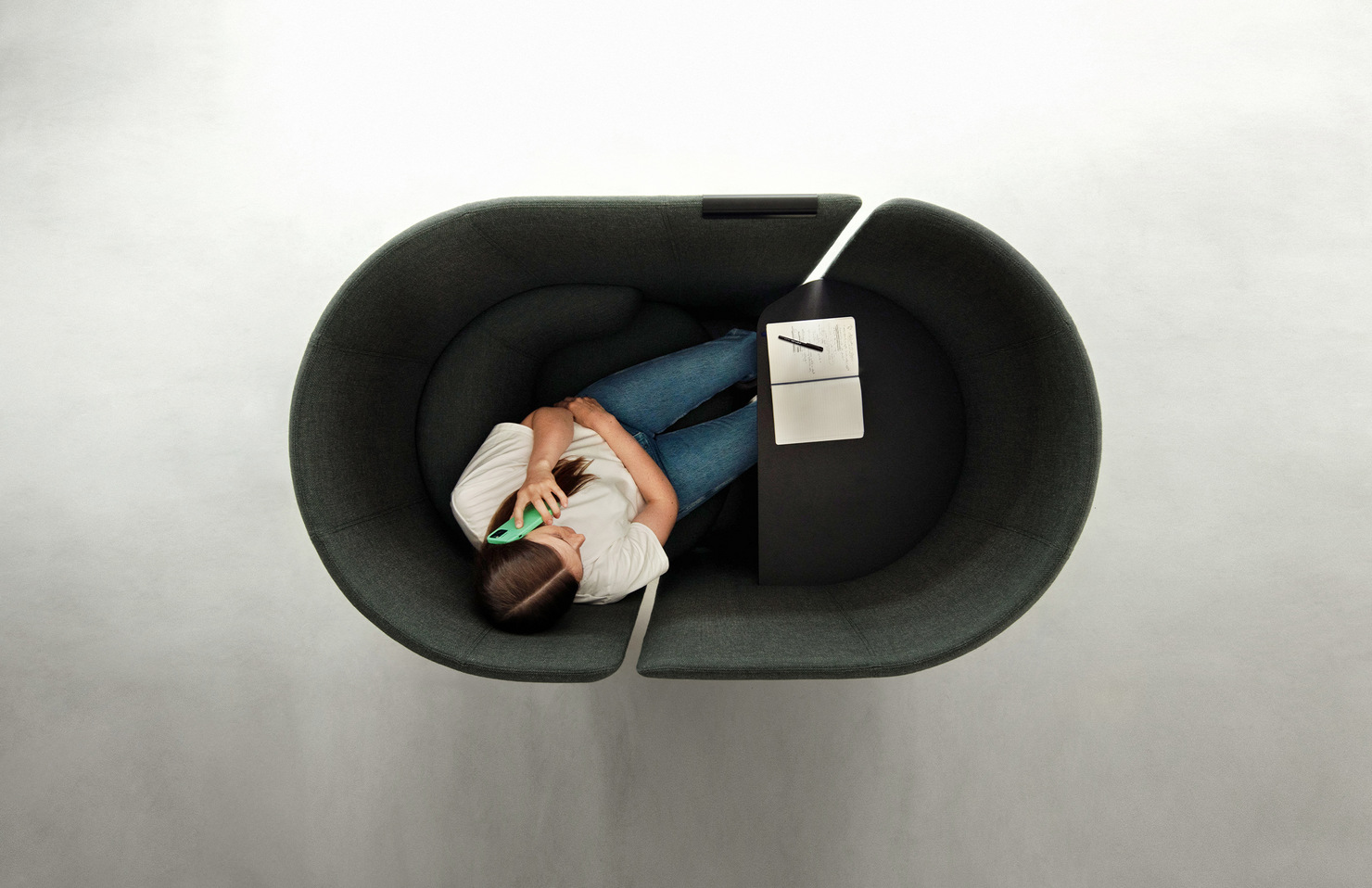 Person on the phone in private within a gray office work pod with a white background