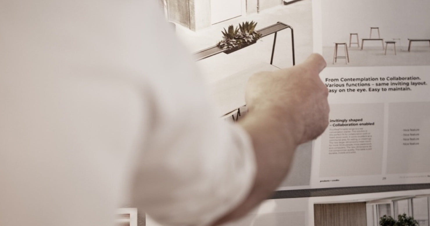 A man pointing to a poster with quotes, highlighting the inviting layout and easy-to-maintain design of Ocee and Four Design.