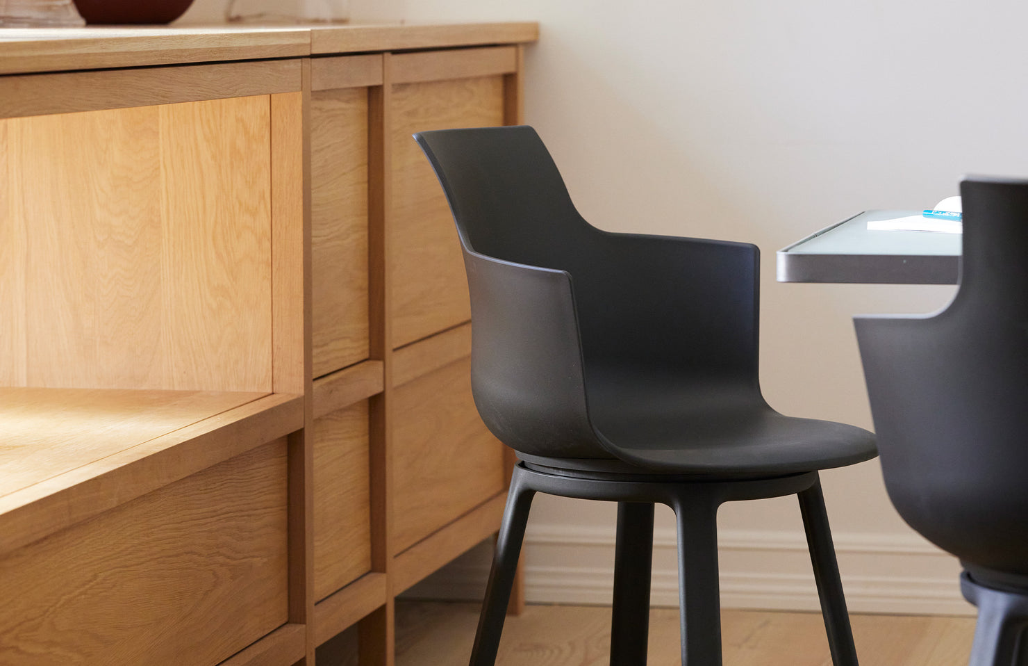 Black chairs in a room with wooden furniture and a white wall.