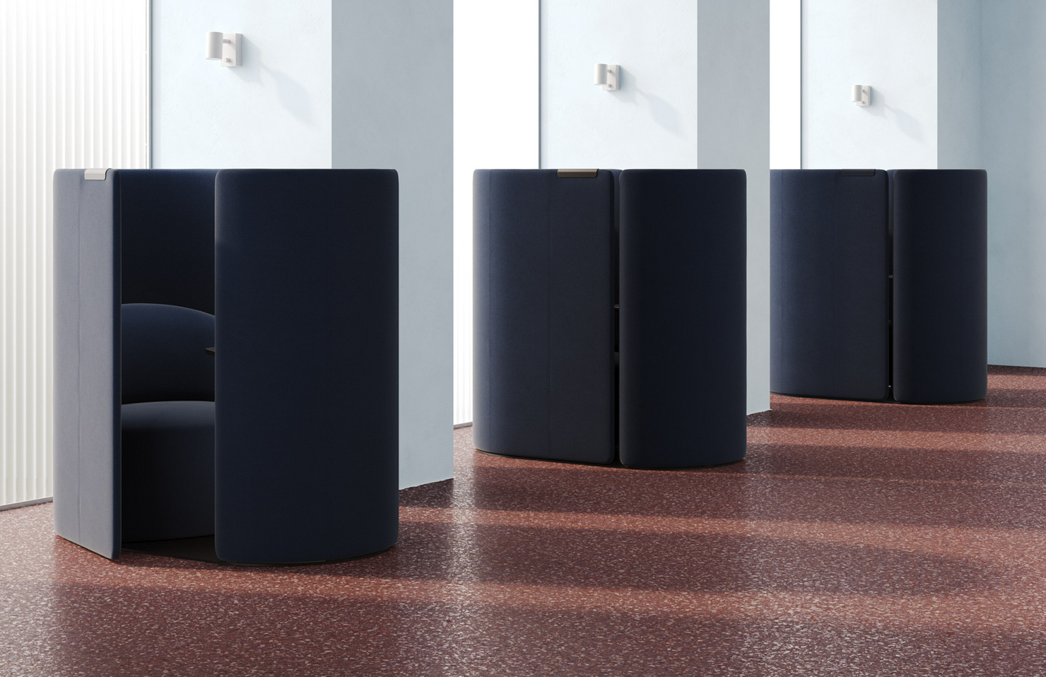 Black cylindrical work pod furniture on a patterned workspace floor with white walls.