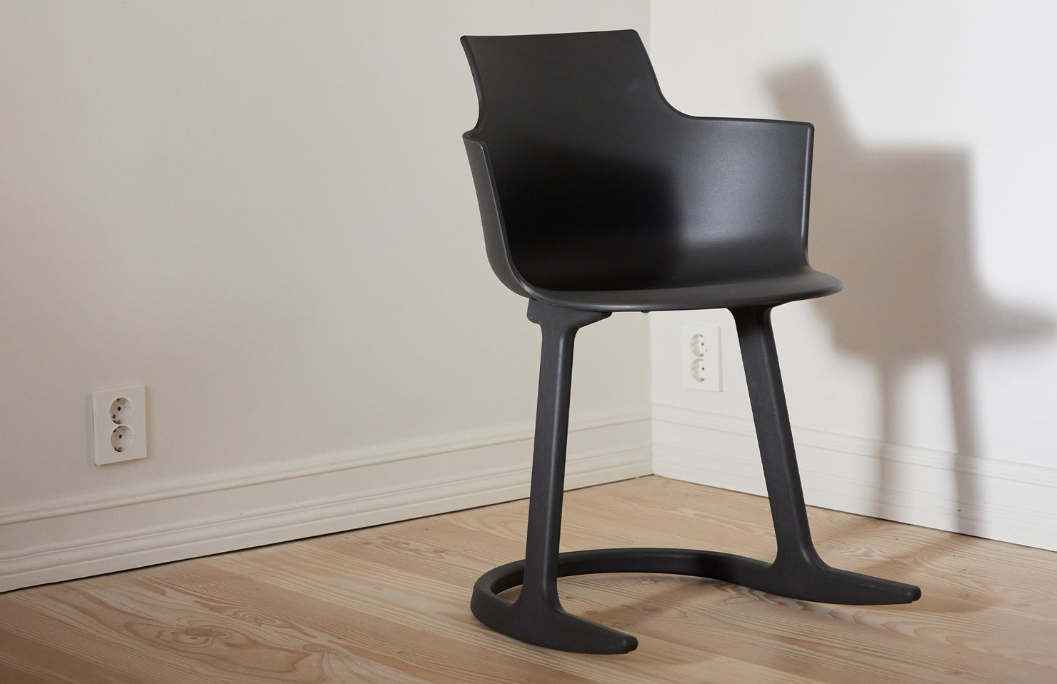 Black chair on a wooden floor against a white wall